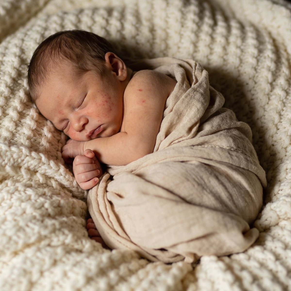 Slapende pasgeboren baby in een artistieke opgerolde houding, gefotografeerd tussen 5 en 15 dagen oud